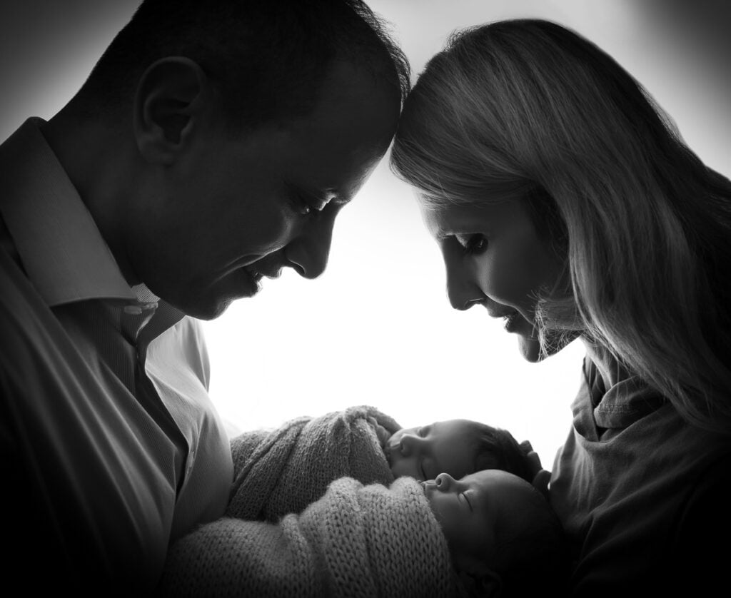 Newborn twin photography family silhouette in black and white: parents forehead to forehead with their newborn twins between them