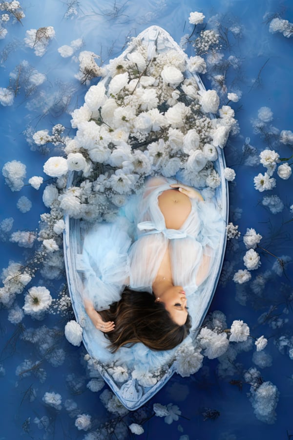 Floating Serenity — Maternity in Bloom on Water A pregnant woman in a sheer blue gown lying in a boat