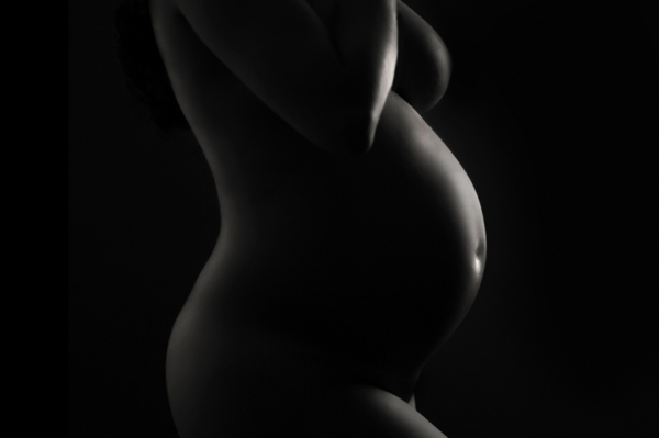 Pure Form — Artistic Maternity Silhouette Black-and-white silhouette of a pregnant woman's torso and belly in a fine art studio setting