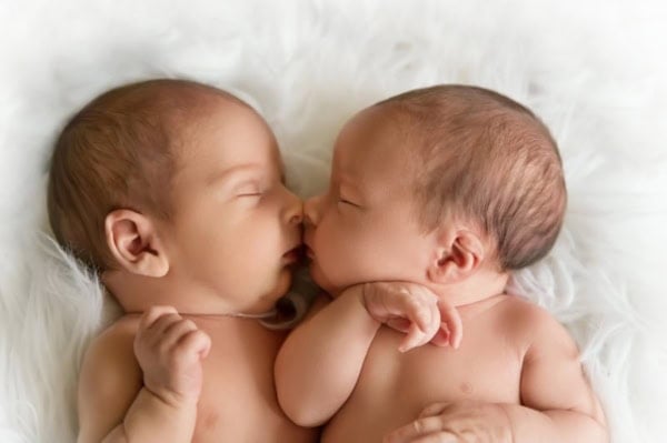 Twin newborn babies sleeping face to face on soft white blanket &mdash; Washington DC twin newborn photography.