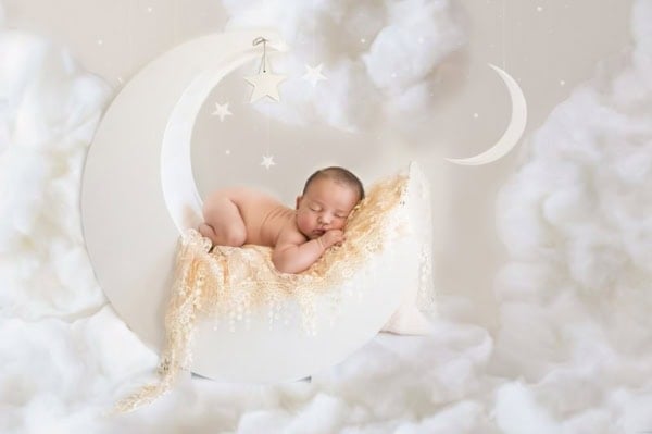 Newborn baby sleeping on a crescent moon prop with lace blanket, clouds, and stars &mdash; Washington DC newborn photographer.