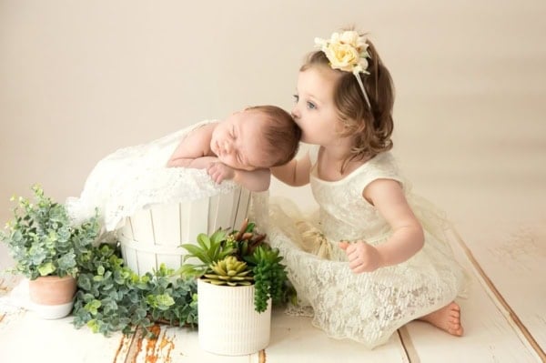 Big sister kissing newborn baby in a white bucket with plants &mdash; Northern Virginia newborn photographer.