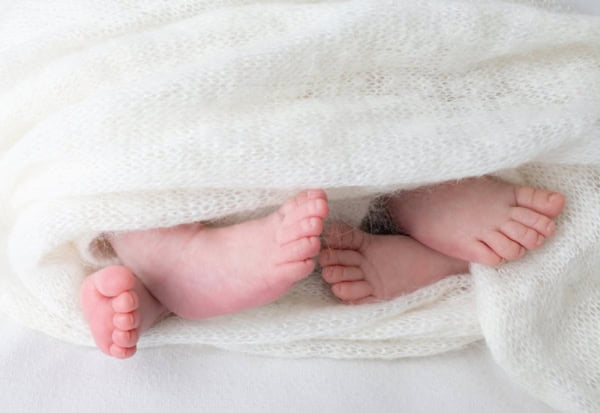 Close-up of newborn baby feet wrapped in a white knitted blanket, photographed by Washington DC newborn photographer.
