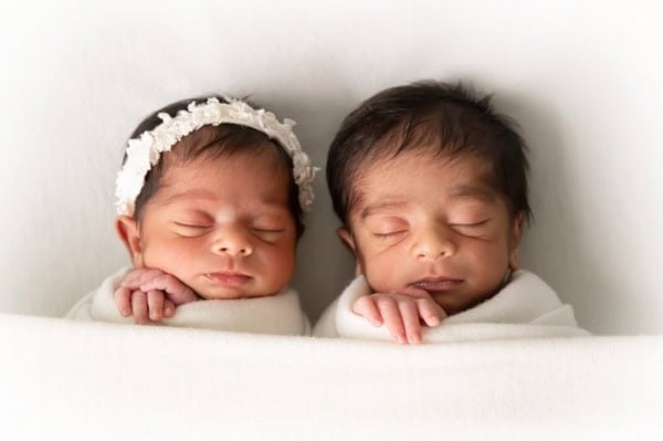 Twin newborn babies wrapped in white, sleeping on a soft surface &mdash; Washington DC newborn photographer.